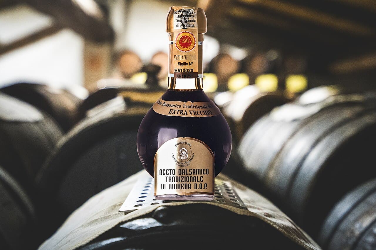 A bottle of extravecchio Aceto Balsamico Tradizionale di Modena DOP resting on aging barrels