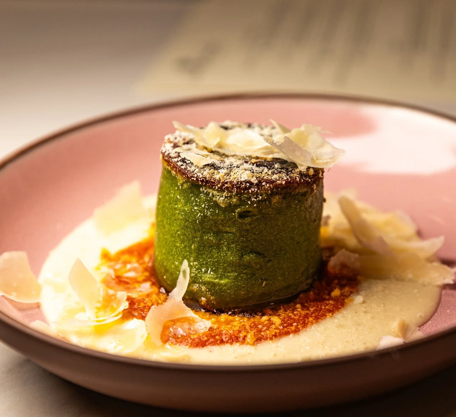 A vibrant green savory cake topped with shaved Parmigiano